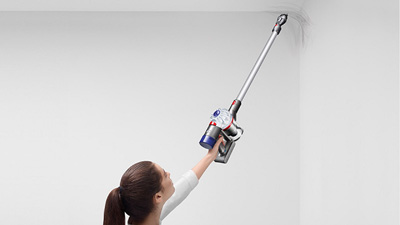 a woman lifting Dyson V7 Animal to cleaning the ceiling